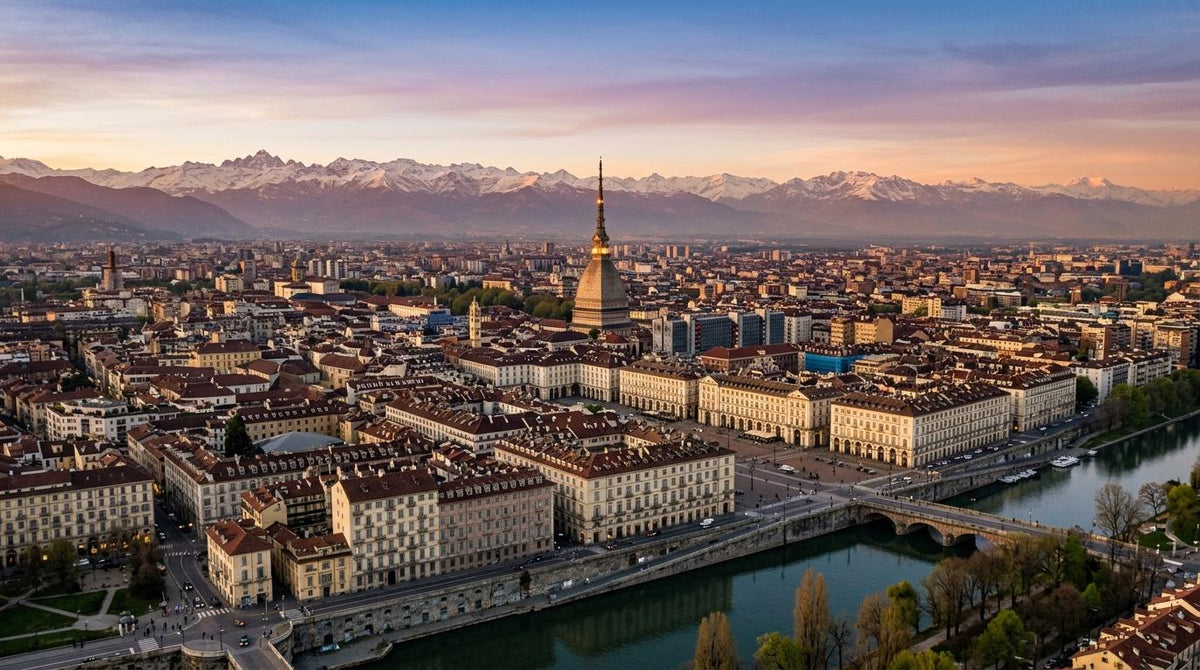 Aerial view of a Turin, Italy with historic buildings, the Mole Antonelliana, the River Po running through the foreground, and snow-capped Alps under a colorful sunset sky.